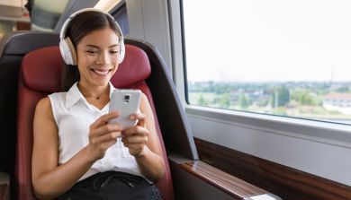 En kvinne med hodetelefoner og sittende på et tog