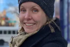 En kvinne med hatt og smilende