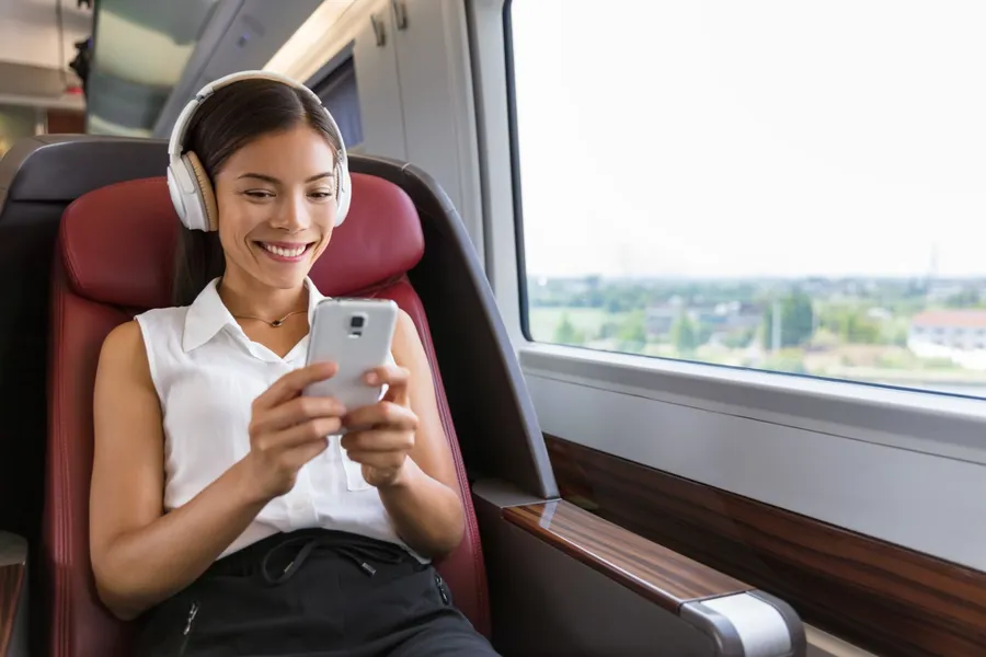En kvinne med hodetelefoner og sittende på et tog