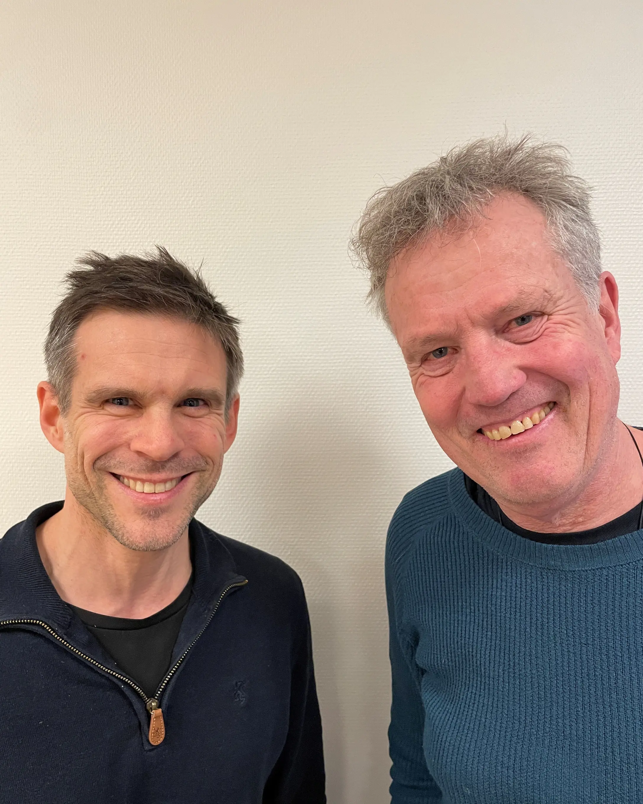 To menn smiler for et bilde