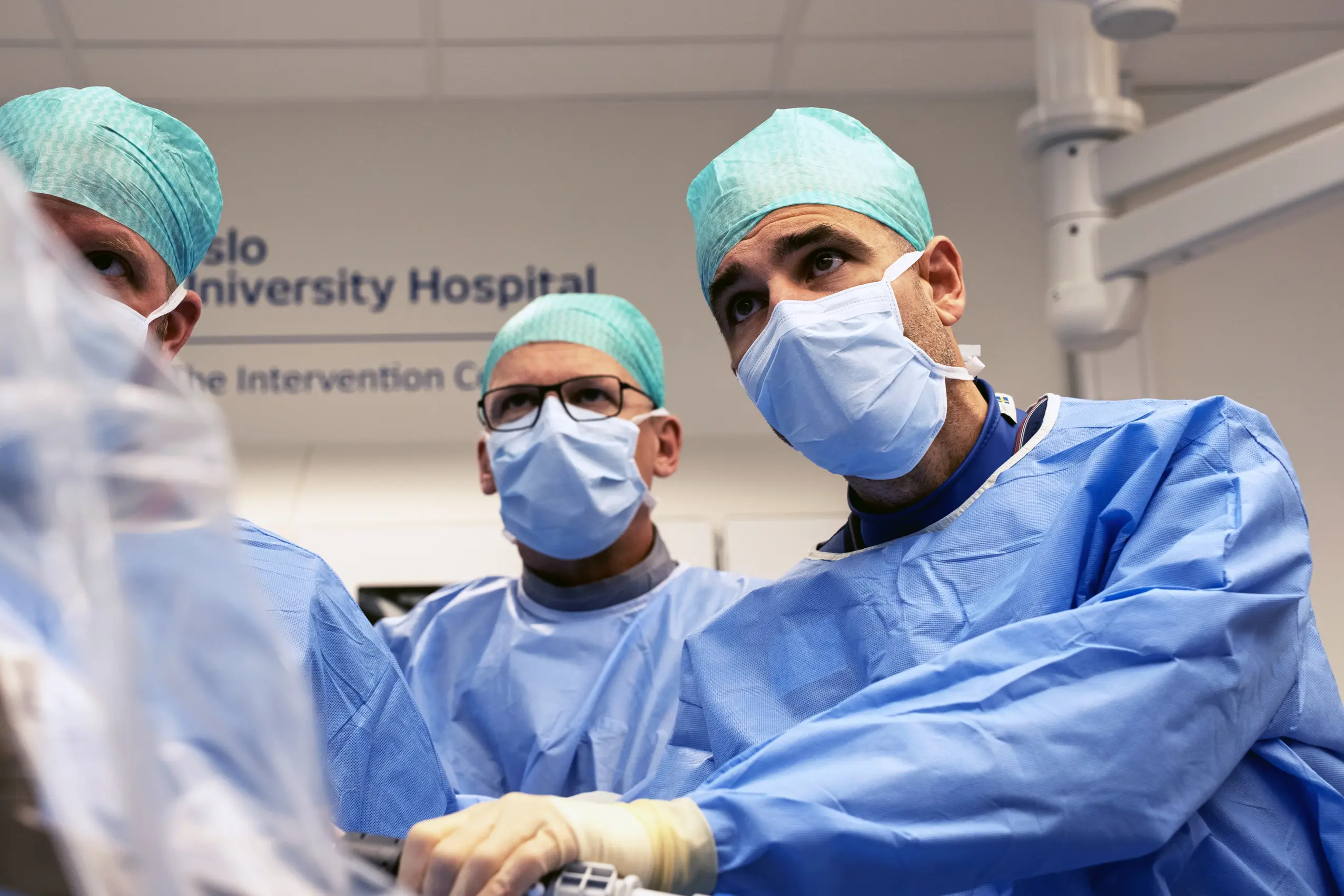tre kirurger i grønt som observerer