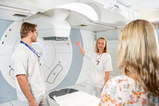 Ansatte viser protonterapimaskinen til en pasient