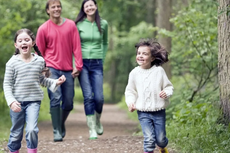 Voksne og barn på tur i skogen.