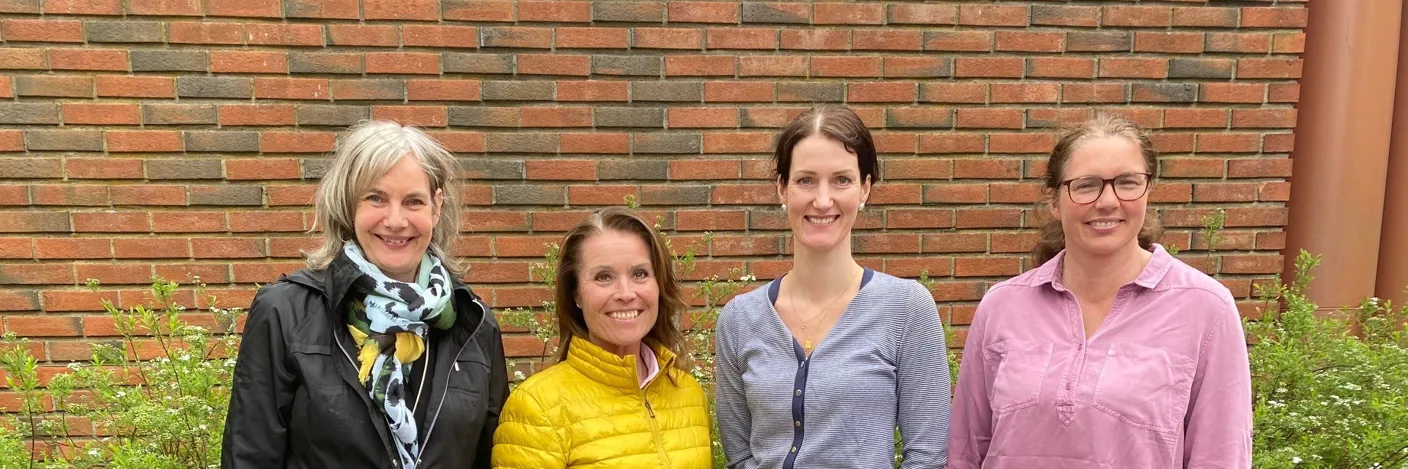 En gruppe kvinner som står foran en murvegg