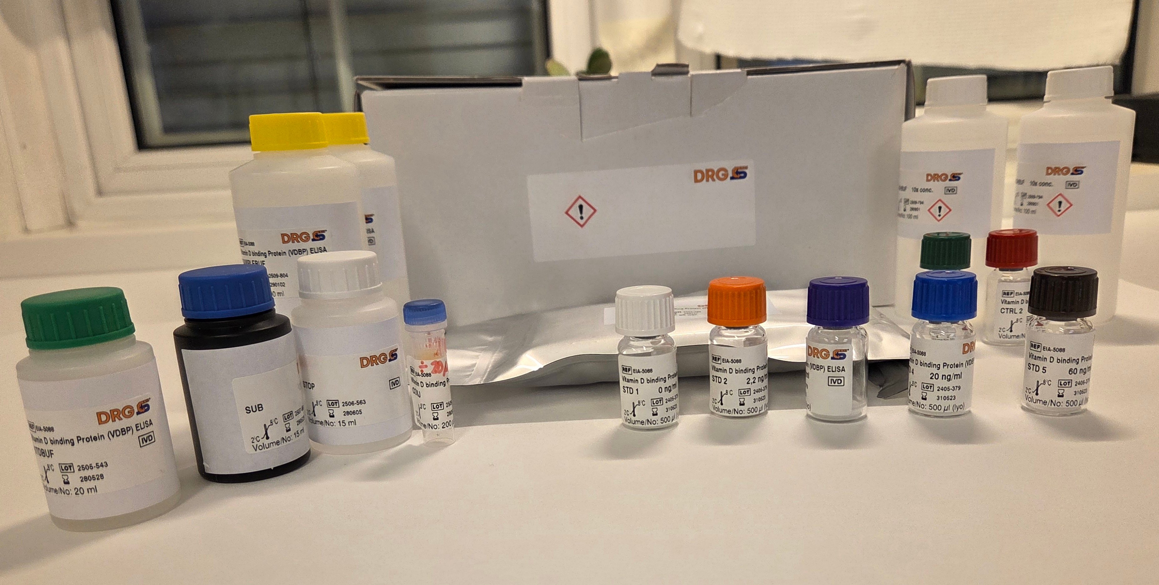 En eske med innhold: Flasker med reagenser og plate til ELISA-analyse