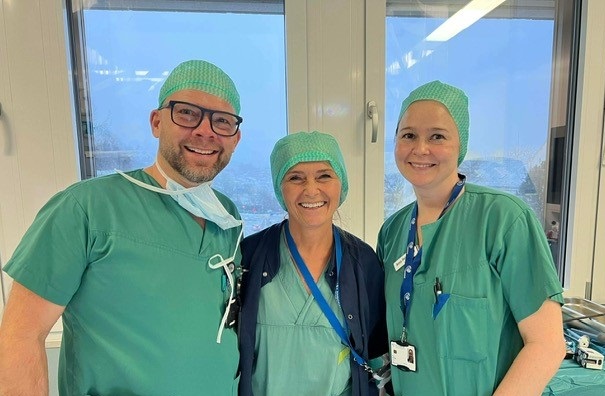 En gruppe mennesker iført kirurgiske uniformer og smilende