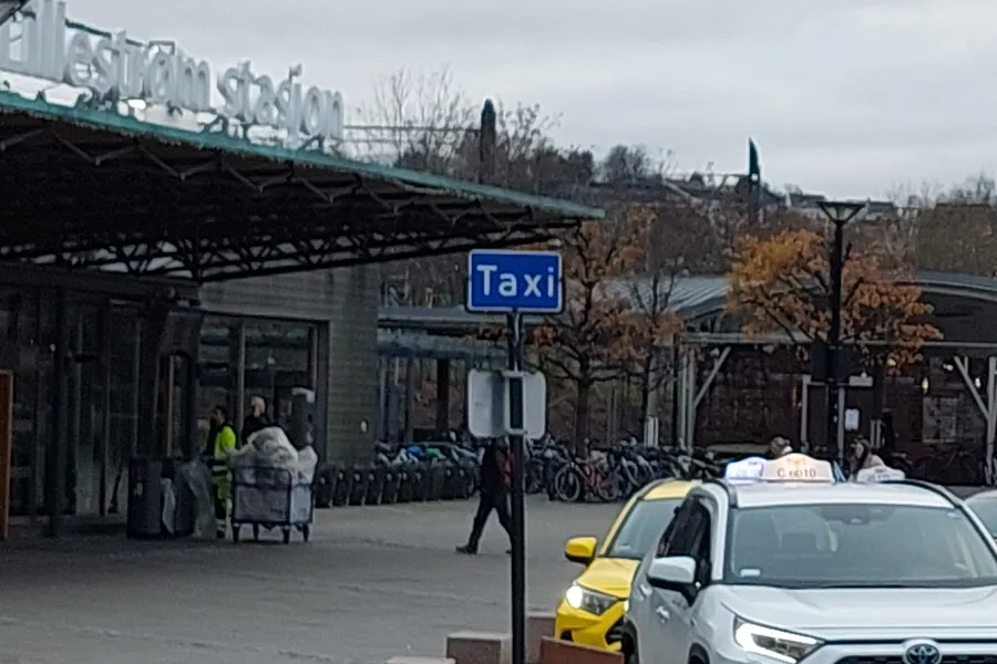 Et gateskilt foran en bygning med stort tak