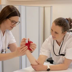 En lege som viser en kvinne noe på telefonen