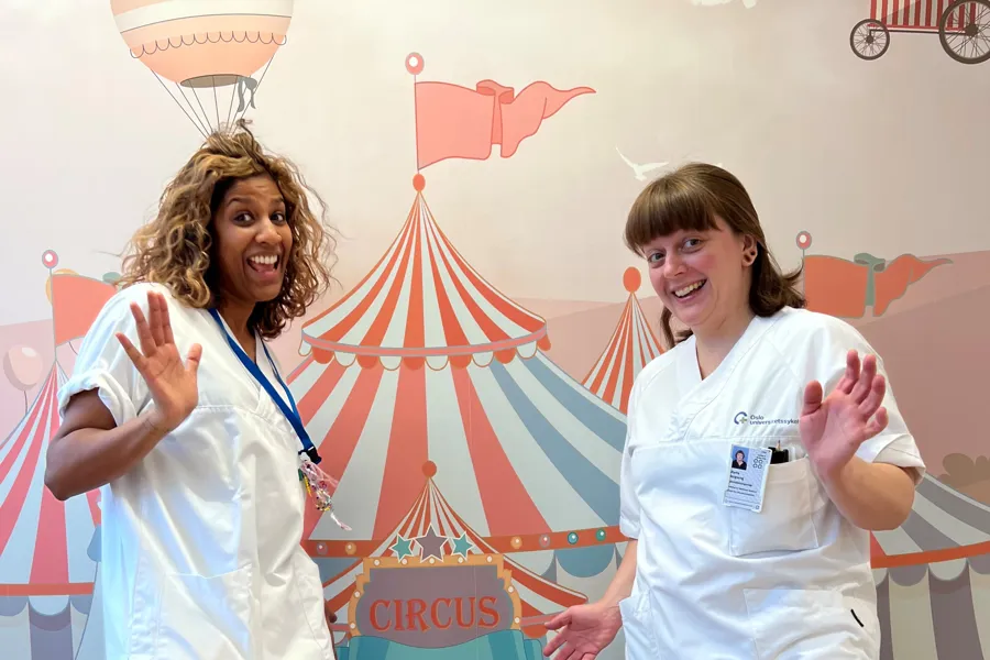 Et par kvinner i hvite sykehusuniformer som vinker