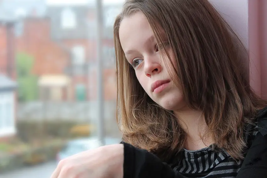 En jente som sitter i vinduskarmen