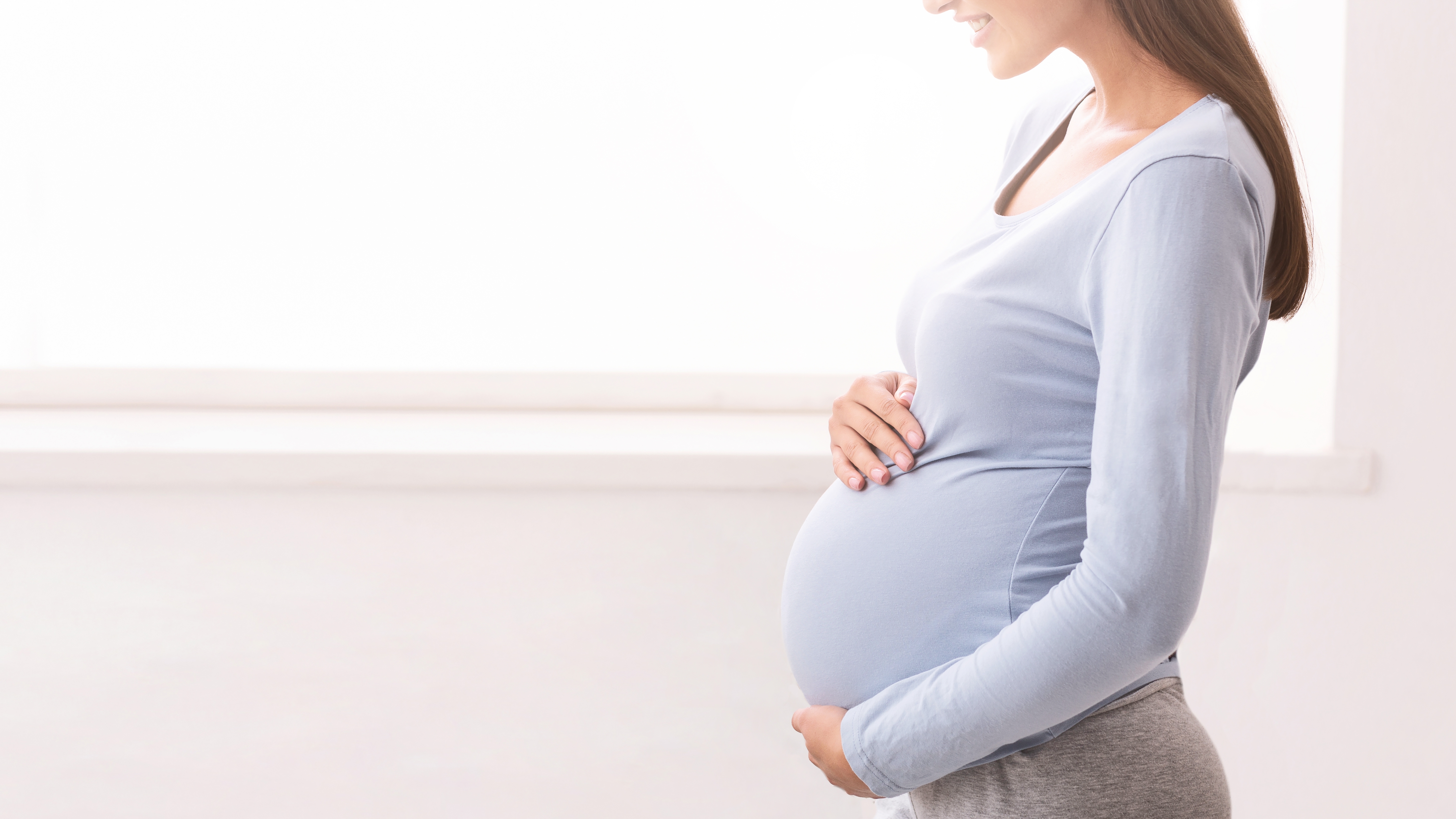 En gravid dame som holder rundt magen sin.