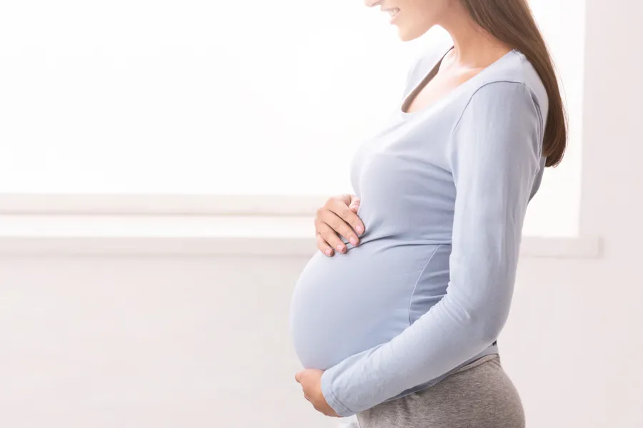 En gravid dame som holder rundt magen sin.