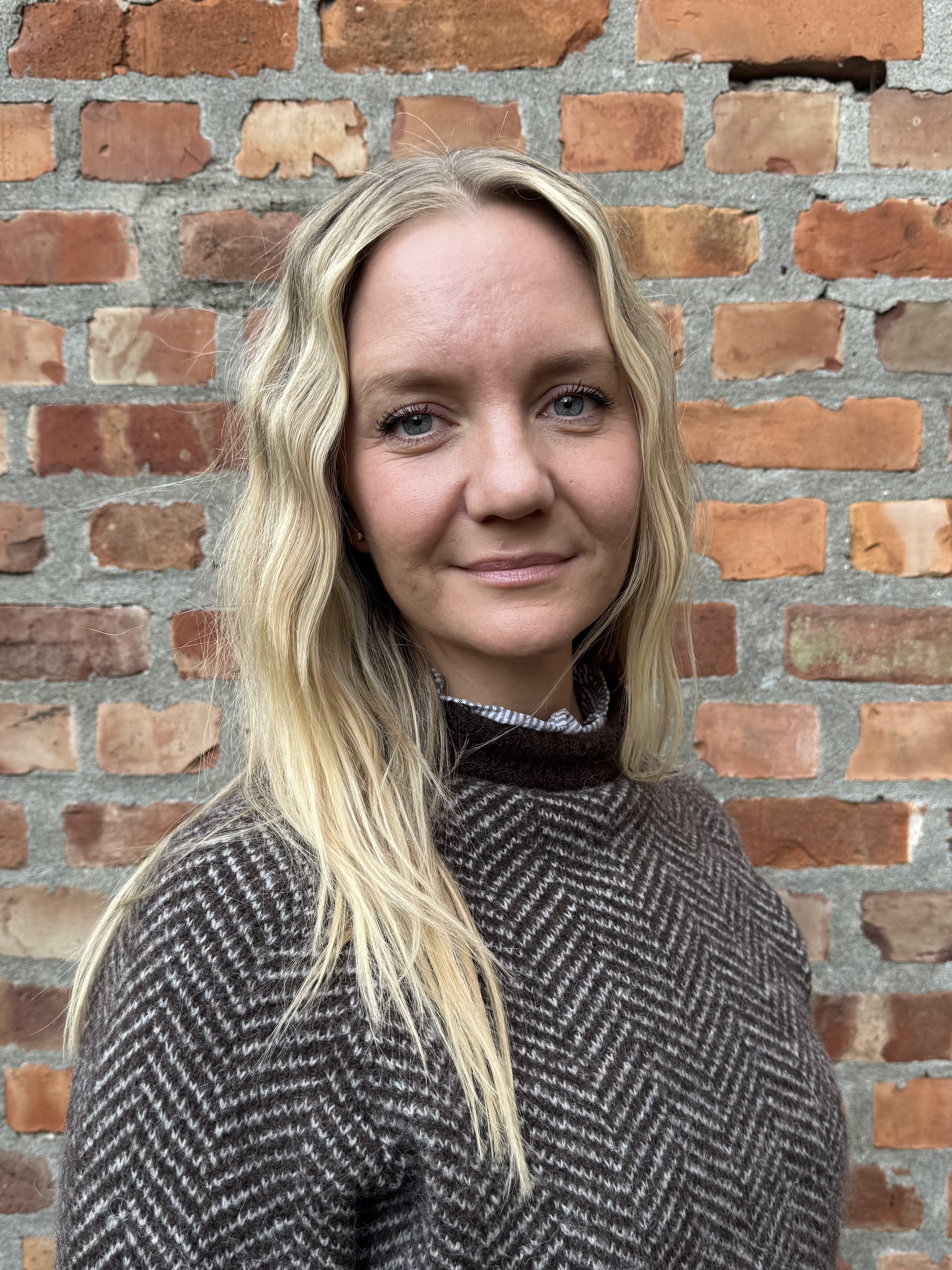 Kvinne foran en murvegg