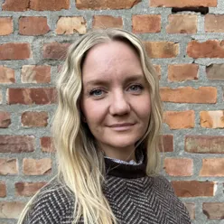 Kvinne foran en murvegg