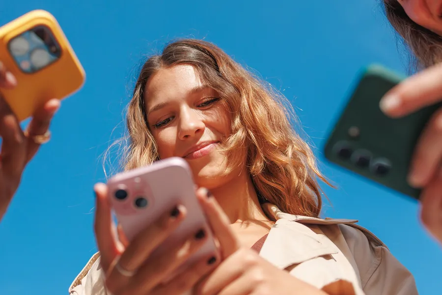 Tre kvinner som holder mobiltelefon