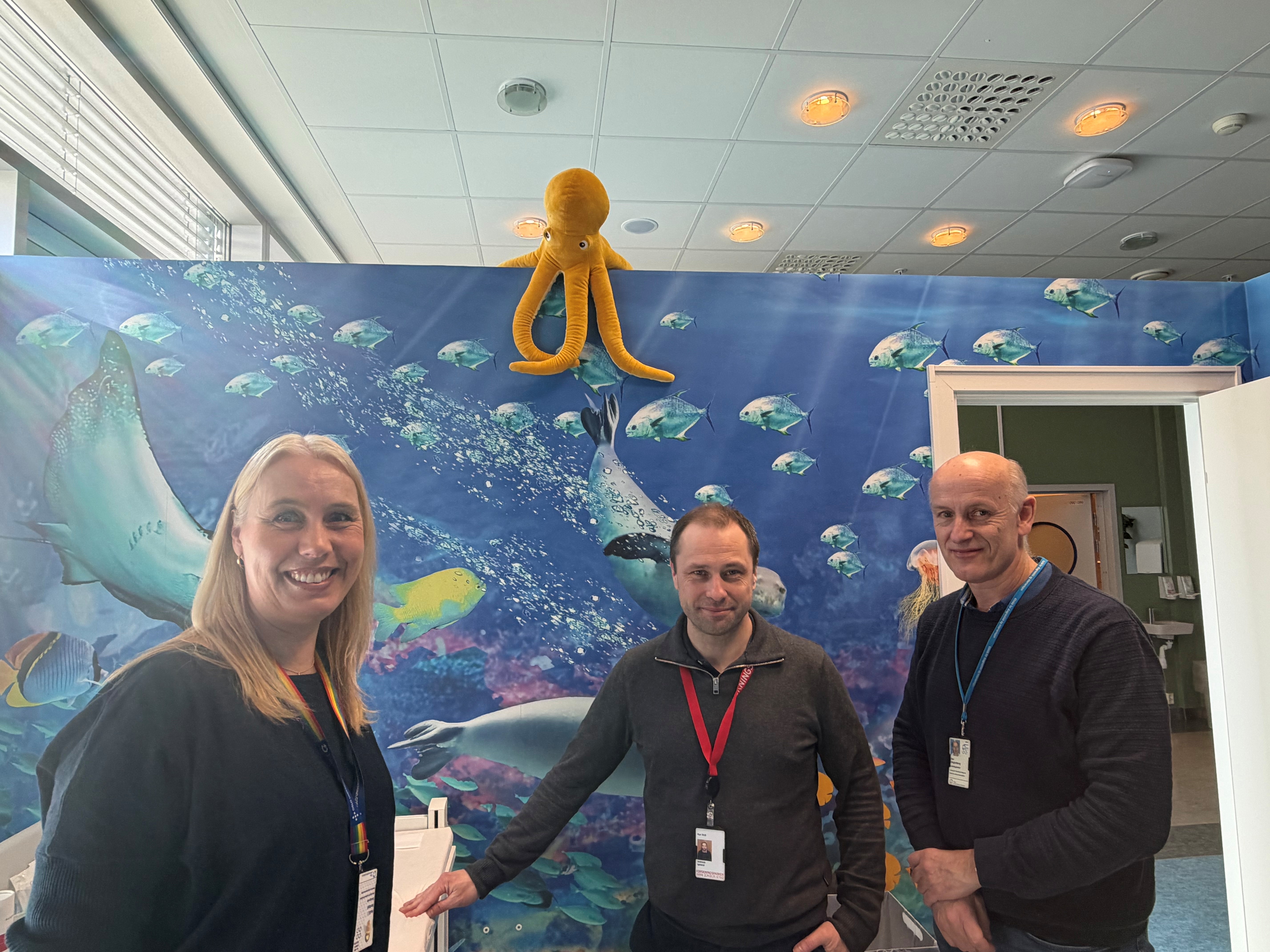 En gruppe mennesker poserer for et bilde foran en blå vegg