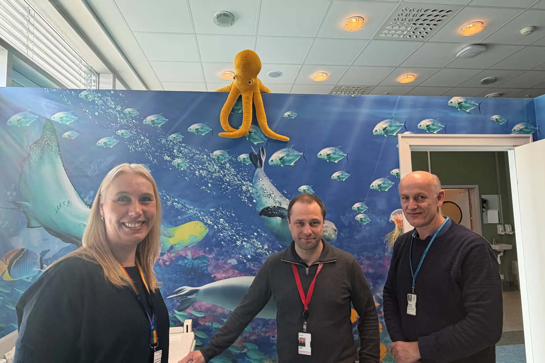 En gruppe mennesker poserer for et bilde foran en blå vegg