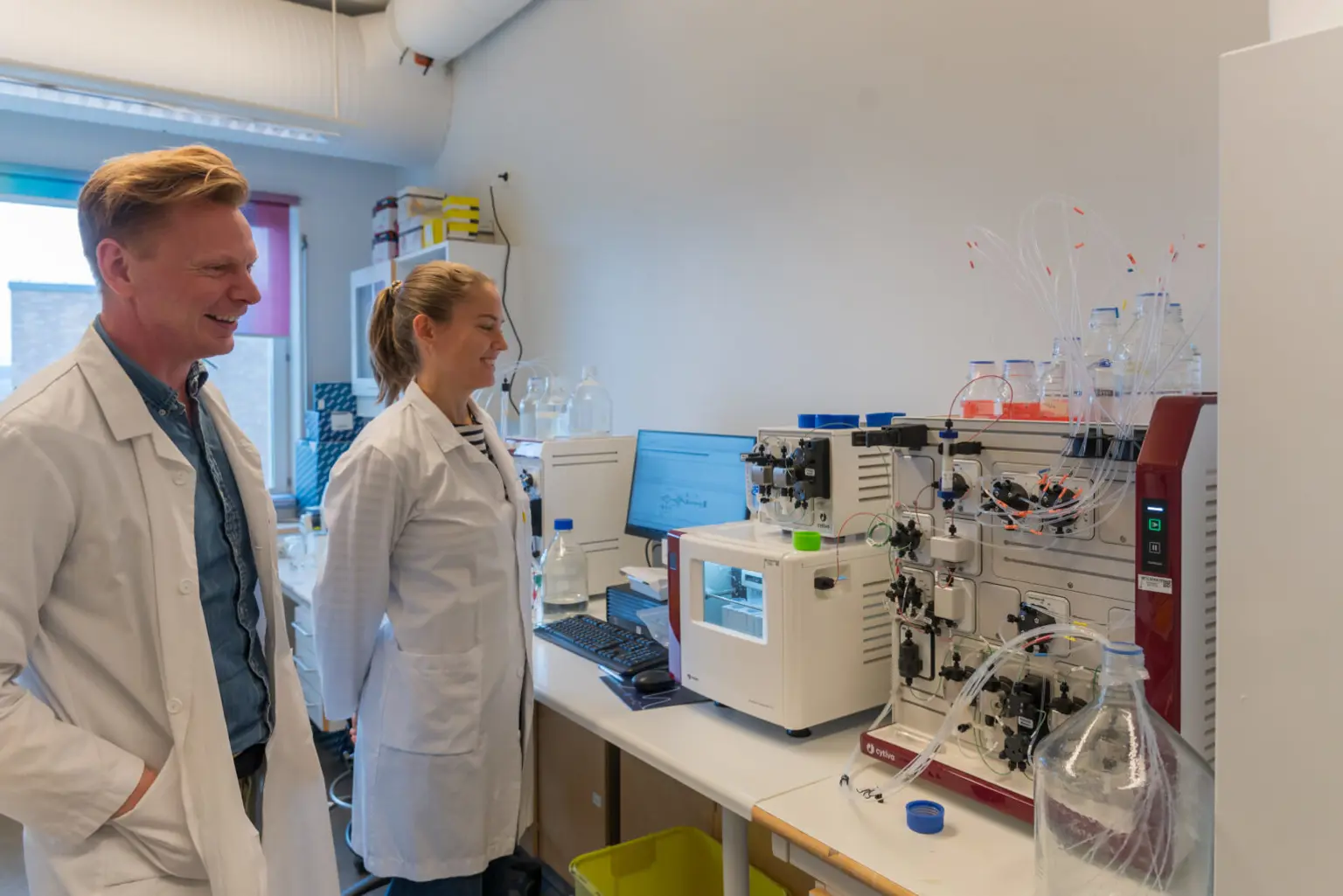 En mann og en kvinne i laboratoriefrakker som ser på en datamaskin