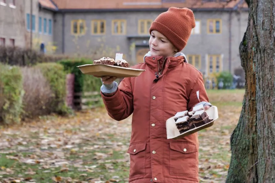 Gutt som holder kaker utenfor skolebygning