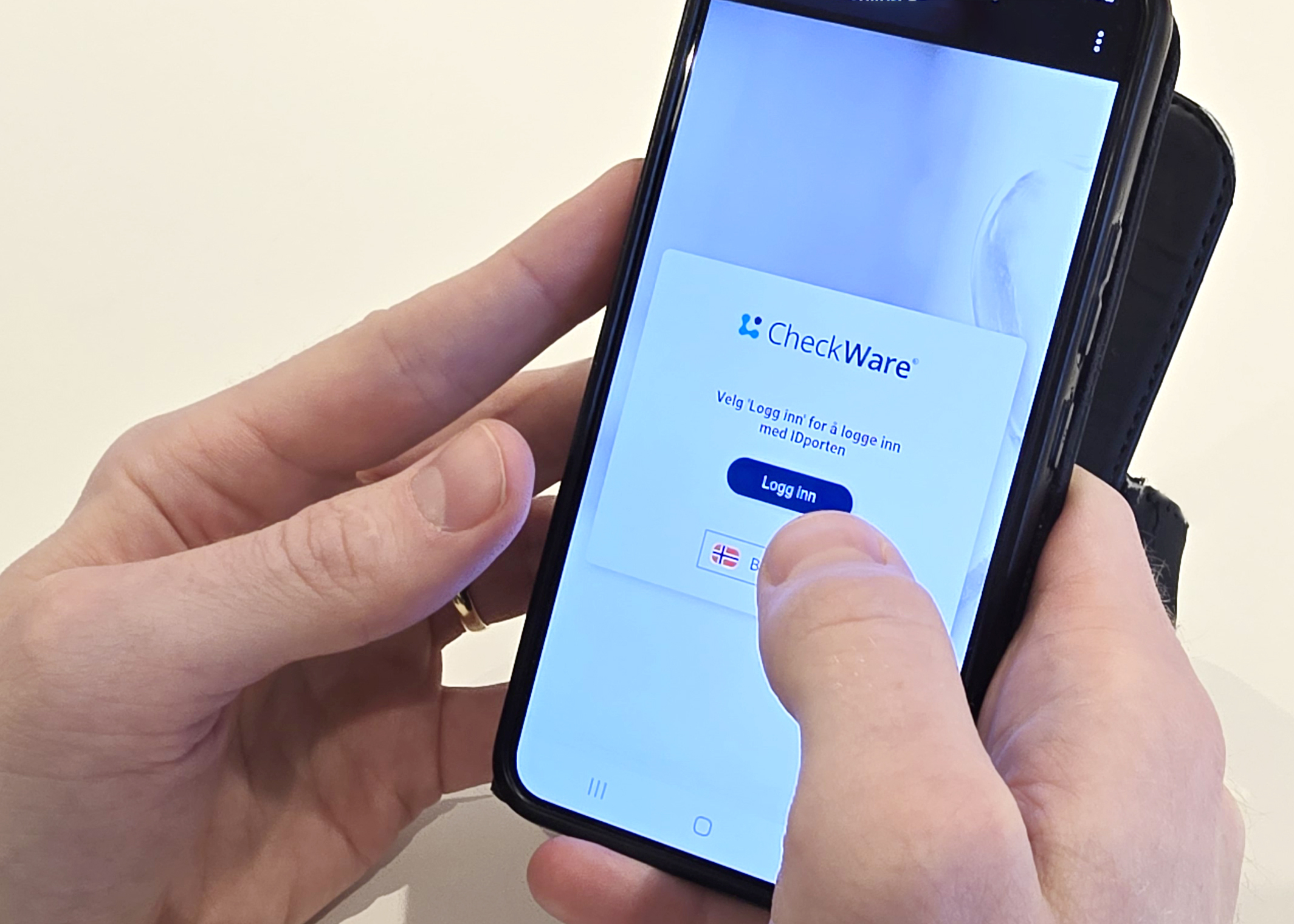 En person som holder en telefon med innlogging til Checkware