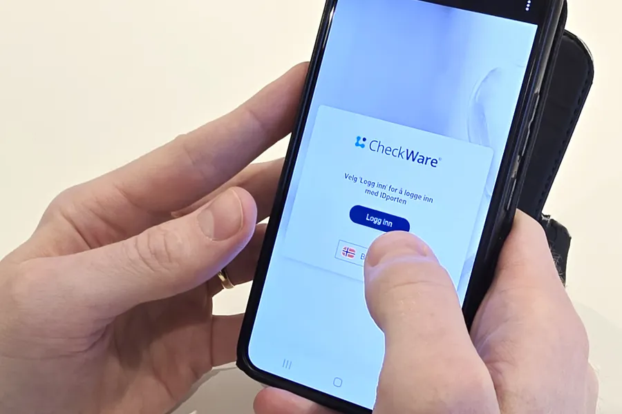 En person som holder en telefon med innlogging til Checkware