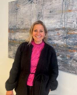 En kvinne som smiler foran en tavle