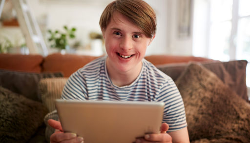 Illustrasjonsbilde av ung mann med utviklingshemming som sitter med skjermbrett i hendene