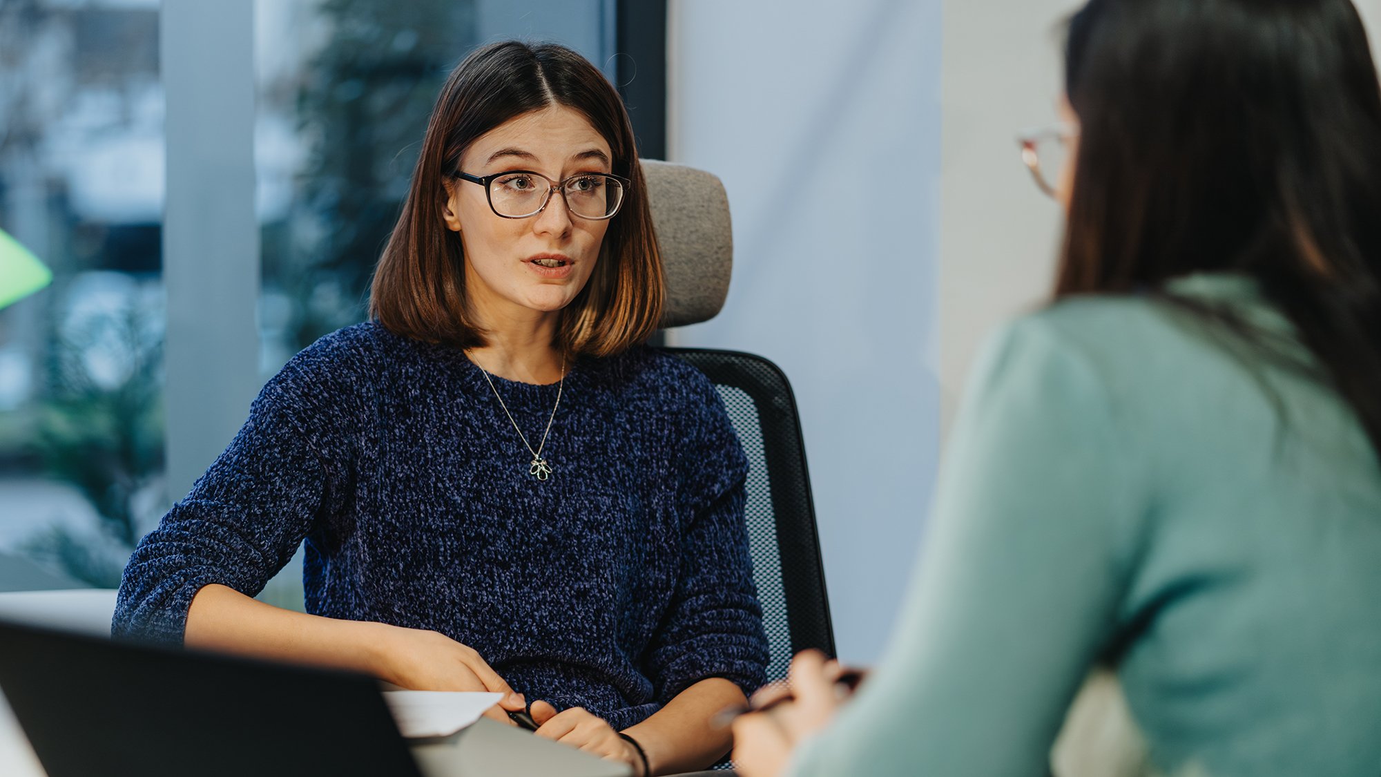 En kvinne med briller som snakker med en annen kvinne