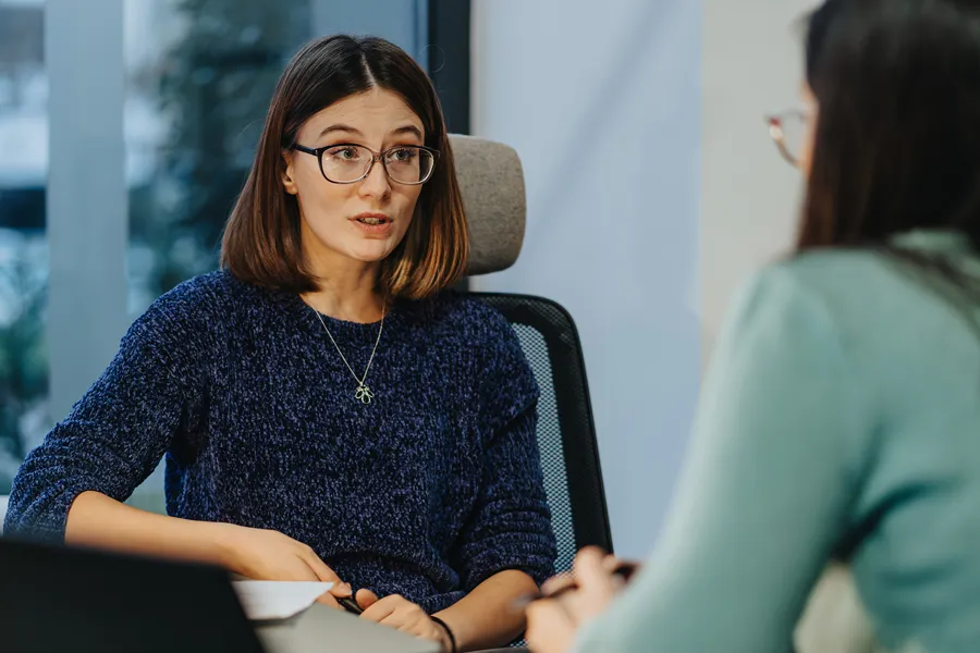 En kvinne med briller som snakker med en annen kvinne