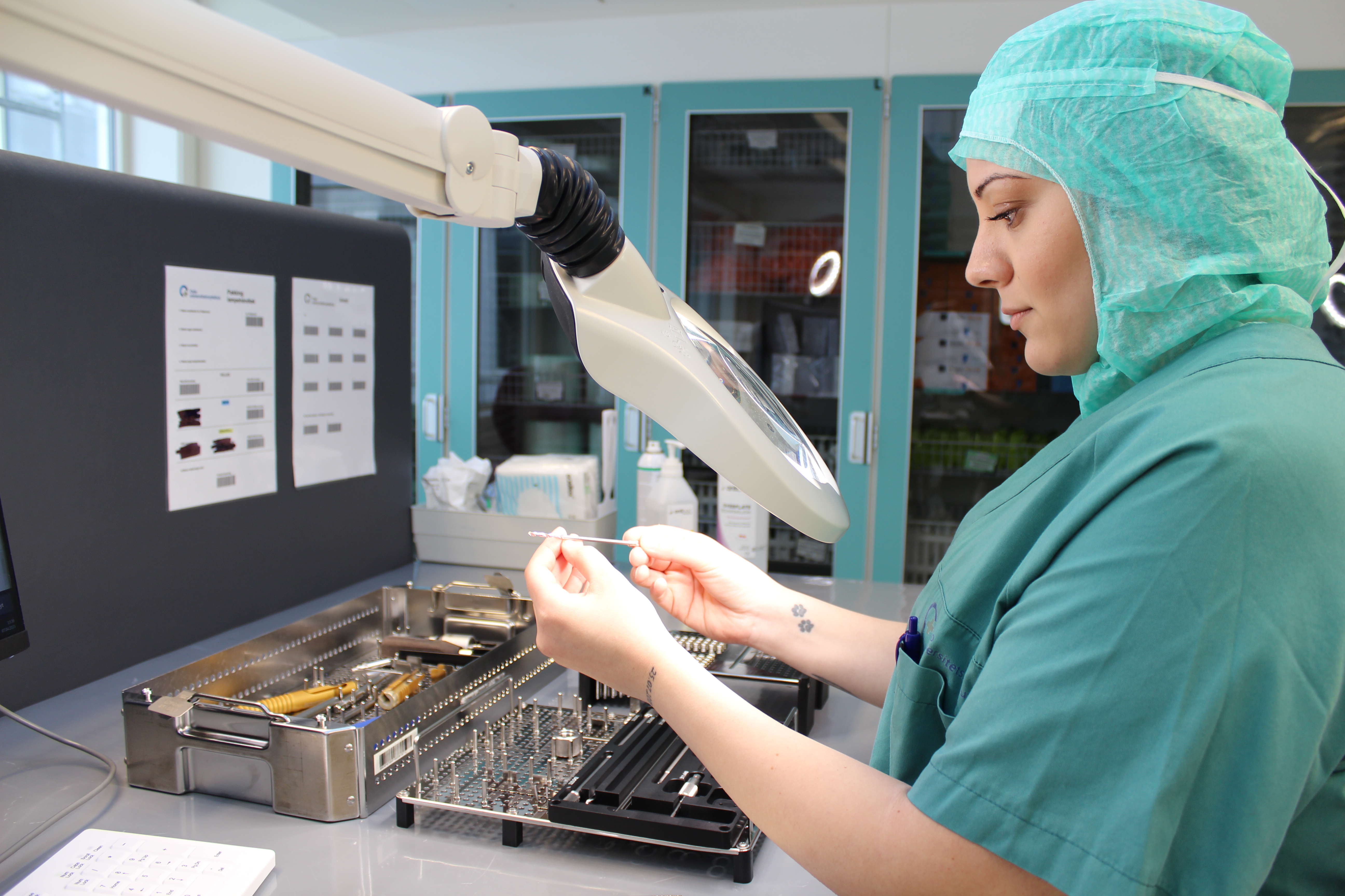 Bilde av helsearbeider i grønn sykehusuniform som inspiserer og steriliserer medisinsk utstyr