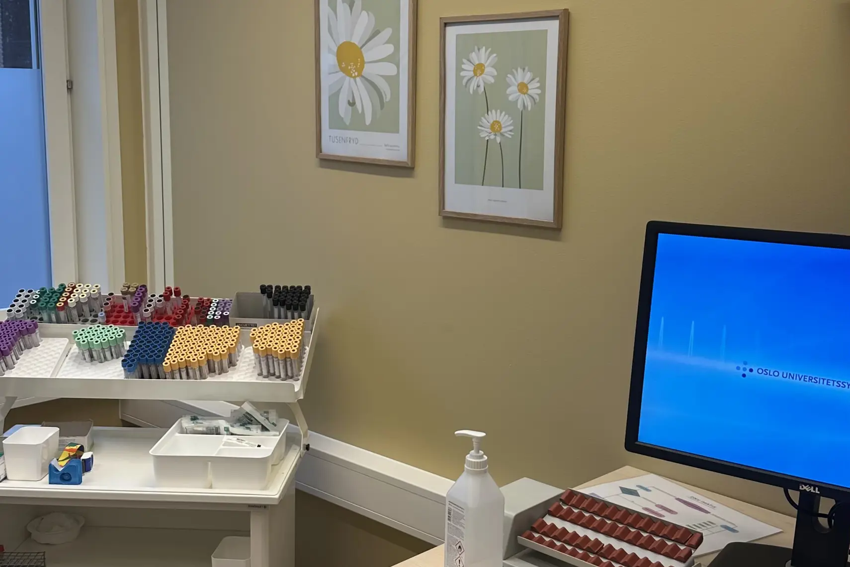 Et skrivebord med en datamaskin og en stol i et rom med vindu