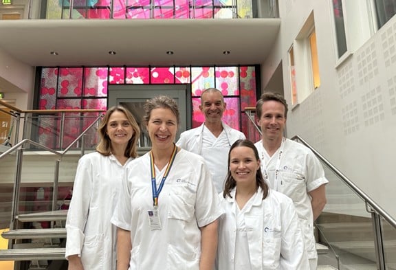 En gruppe mennesker iført hvite laboratoriefrakker og merke