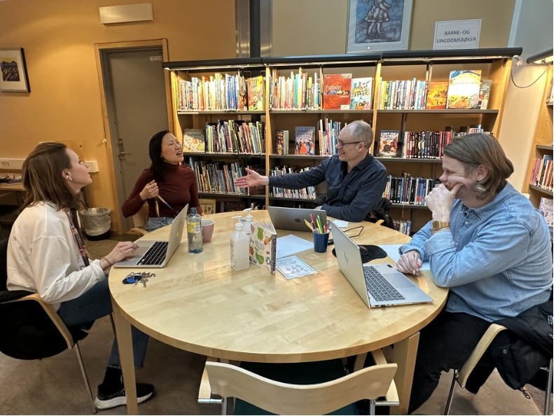 En gruppe mennesker som sitter rundt et bord med bærbare datamaskiner