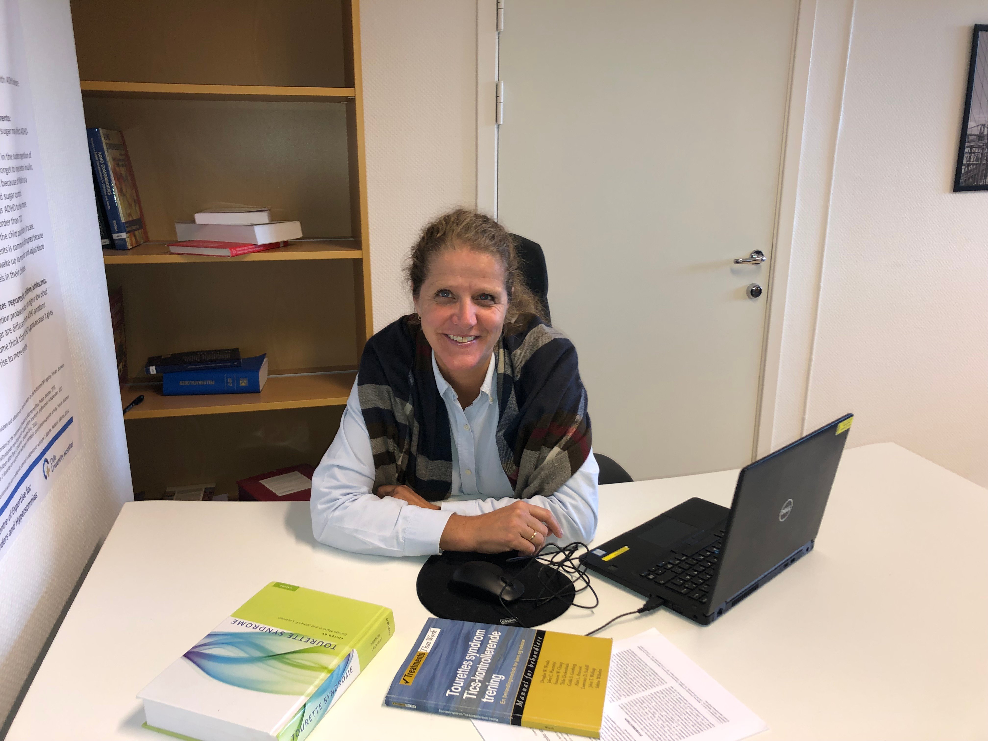 En person som sitter ved et skrivebord med en bærbar PC og papirer