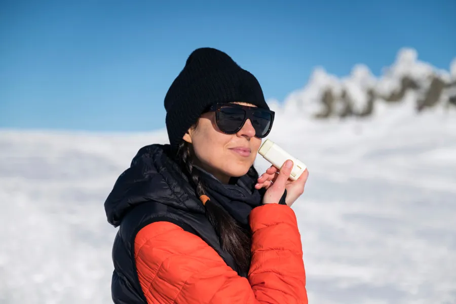 Dame som er på tur på fjellet og smører seg med solkrem