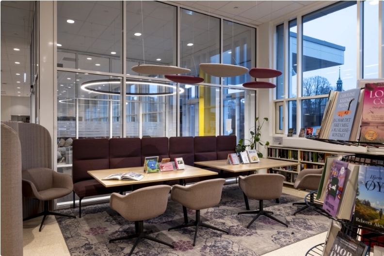 Et bibliotek med et stort bord, sofa og stoler