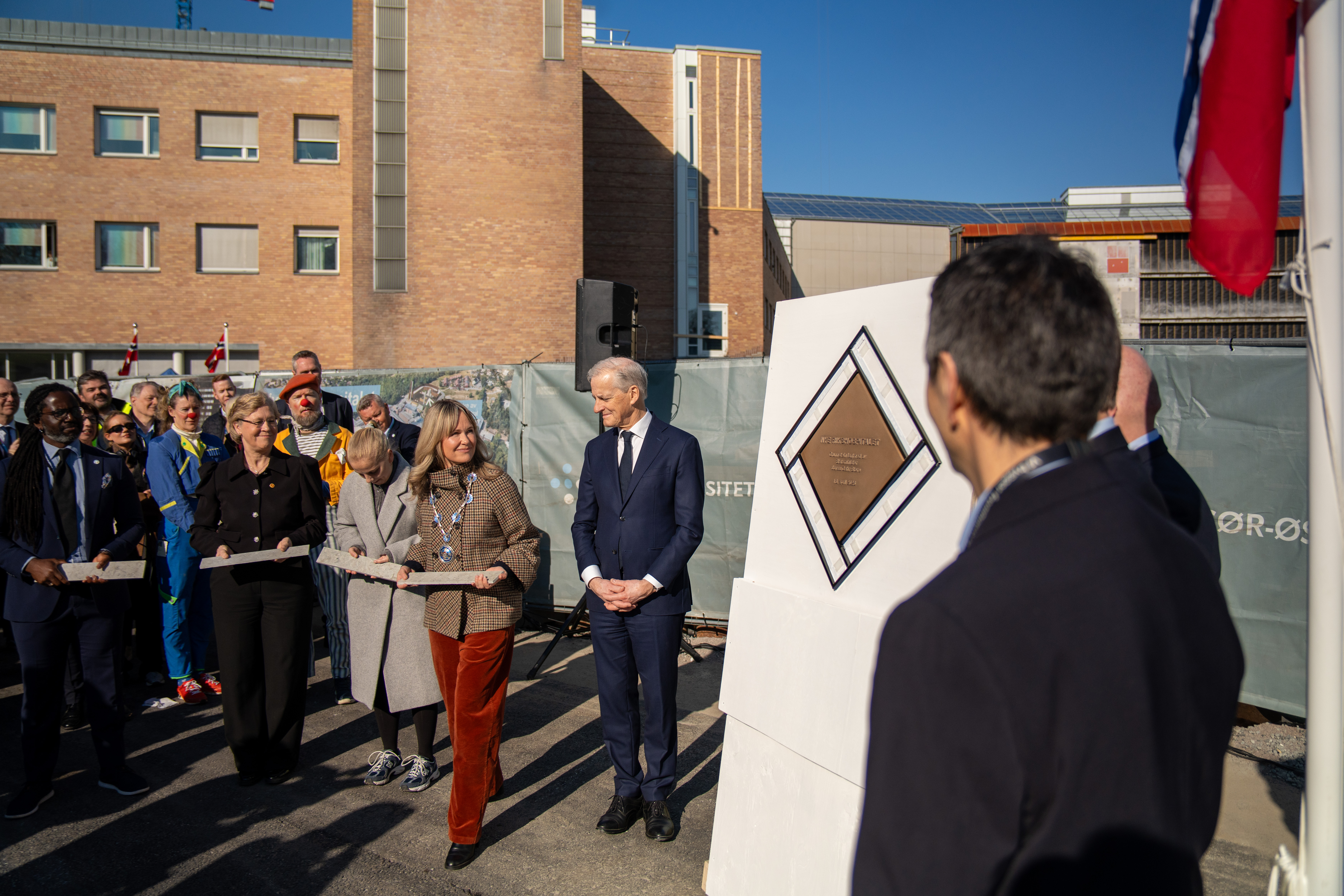 Oslos ordfører, Anne Lindboe, og statsminister Jonas Gahr Støre står ved siden av grunnsteinen sammen med mange mennesker.