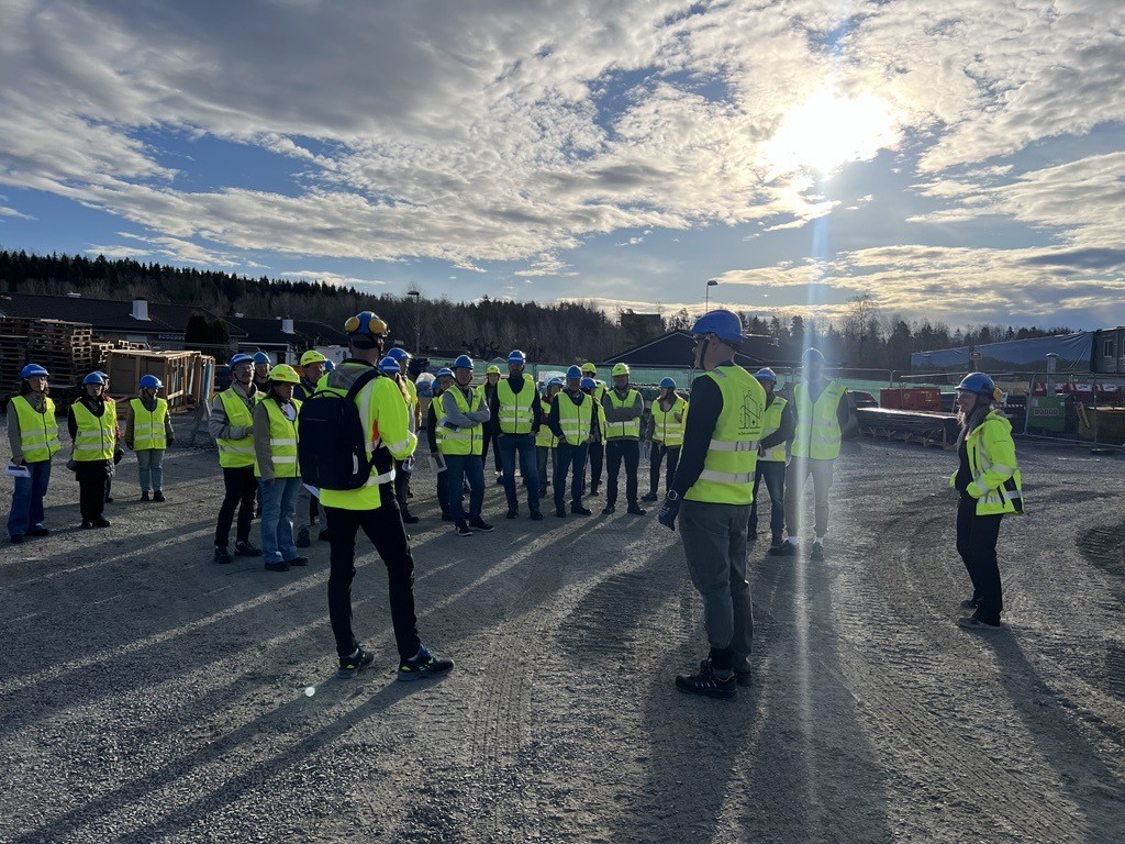 En gruppe mennesker i gule vester som står på en vei