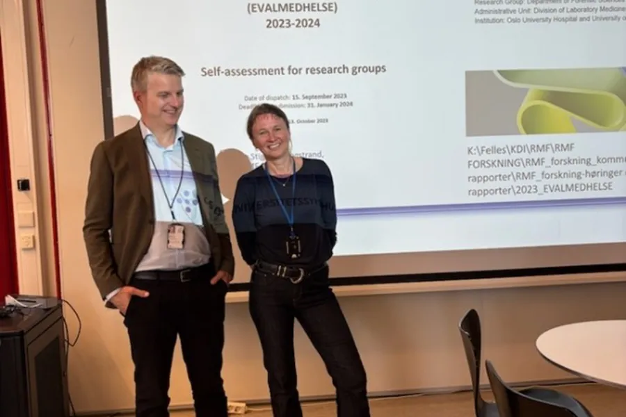 En mann og en kvinne som står foran en storskjerm