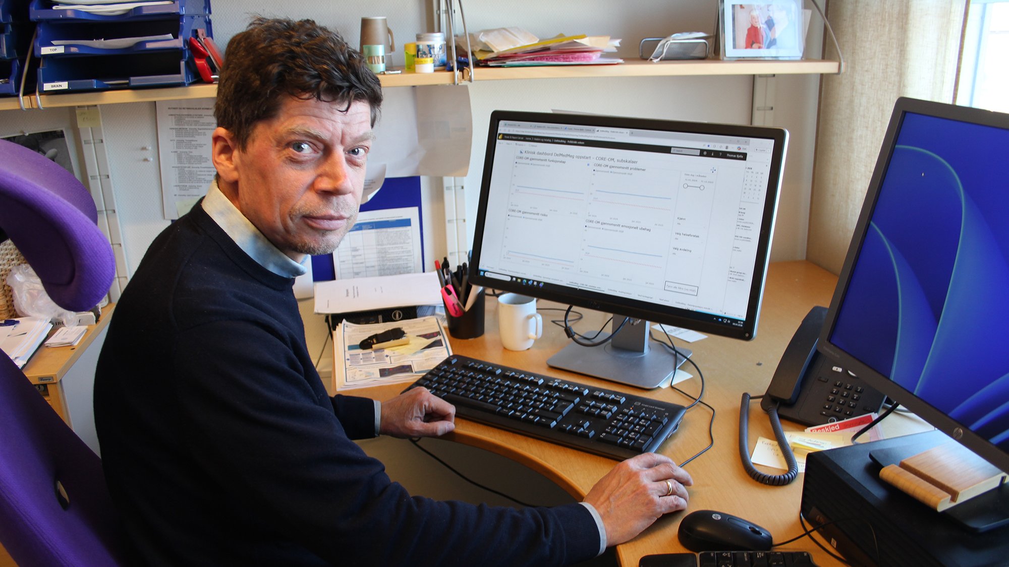 Thomas Bjella som sitter ved et skrivebord med en datamaskin