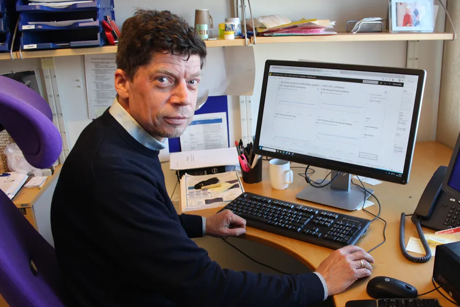 Thomas Bjella som sitter ved et skrivebord med en datamaskin