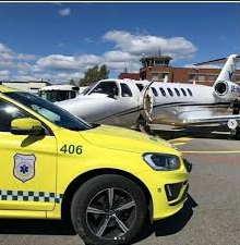 En gul bil parkert ved siden av et fly