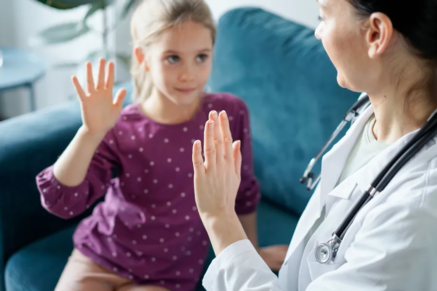 Jente gir high five til lege