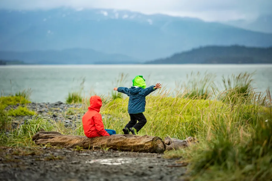 To barn ute i naturen langs vannkanten med regntøy