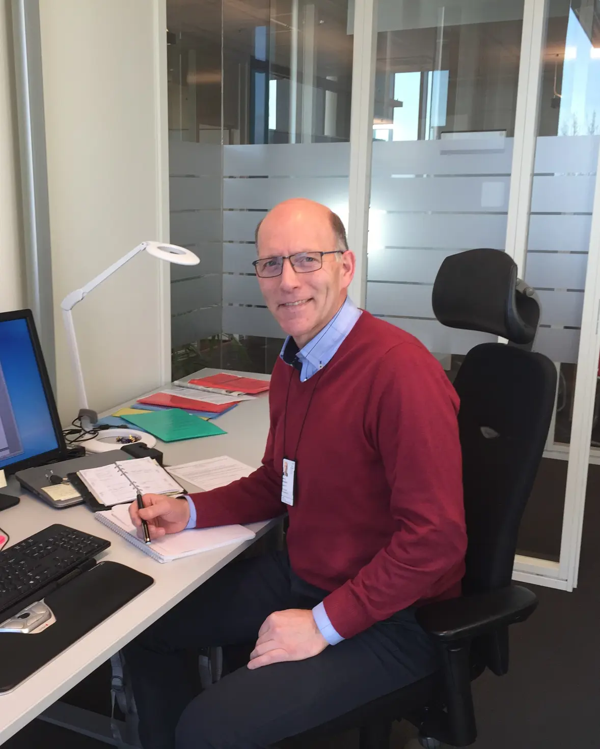 En mann som sitter ved et skrivebord med en datamaskin og et tastatur