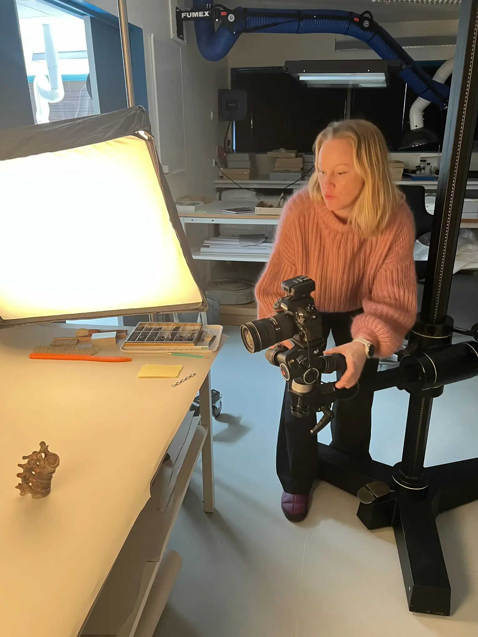 En person som sitter ved et skrivebord med et kamera