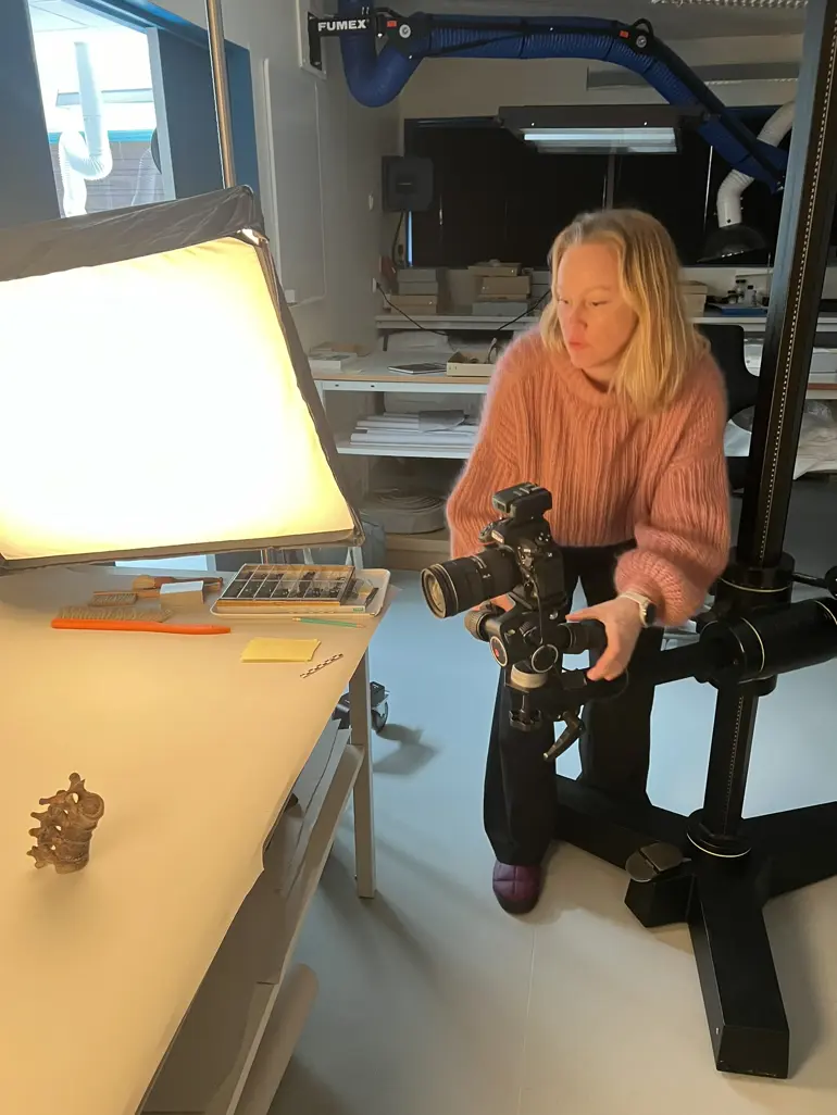 En person som sitter ved et skrivebord med et kamera