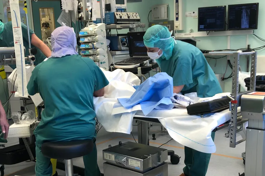 Et par personer i kirurgiske scrubs som jobber i et rom