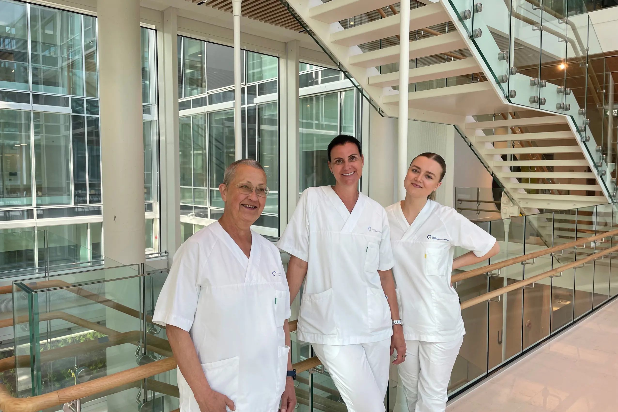 En gruppe mennesker i hvite labfrakker står i et rom med glassvegger og glassgulv