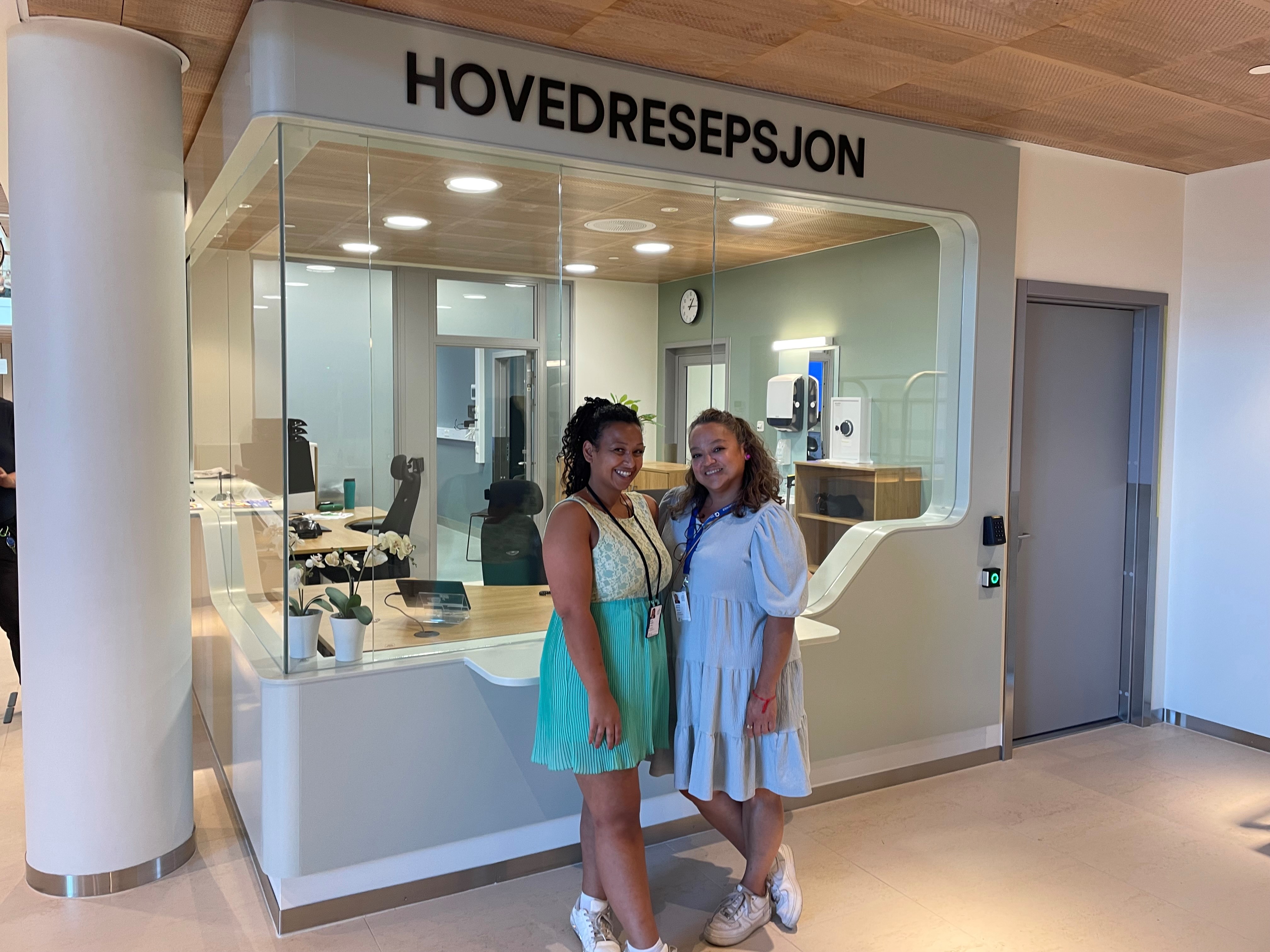 Et par kvinner poserer for et bilde foran en butikk